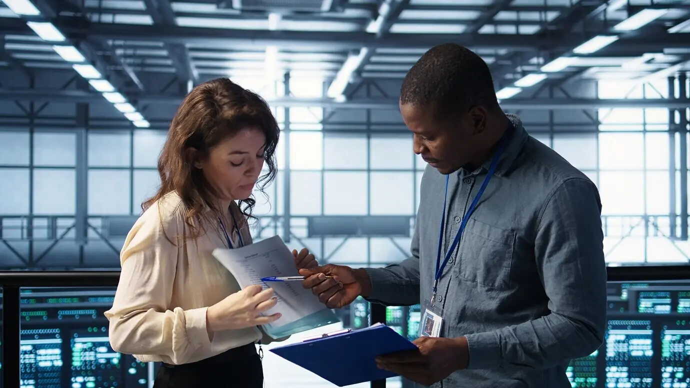 Группа супервайзеров дата-центра читает бумажные документы.